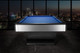 Wide profile view of the Doc & Holliday Poshy Reverse Rainbow Slate Pool Table, showing its brushed silver metallic base, reverse rainbow accents, Euro Blue Championship felt, and matte black upper rails, staged on a concrete floor with a clean modern backdrop wall. Wide profile view of the Doc & Holliday Poshy Reverse Rainbow Slate Pool Table, showing its brushed silver metallic base, reverse rainbow accents, Euro Blue Championship felt, and matte black upper rails, staged on a concrete floor with a clean modern backdrop wall.